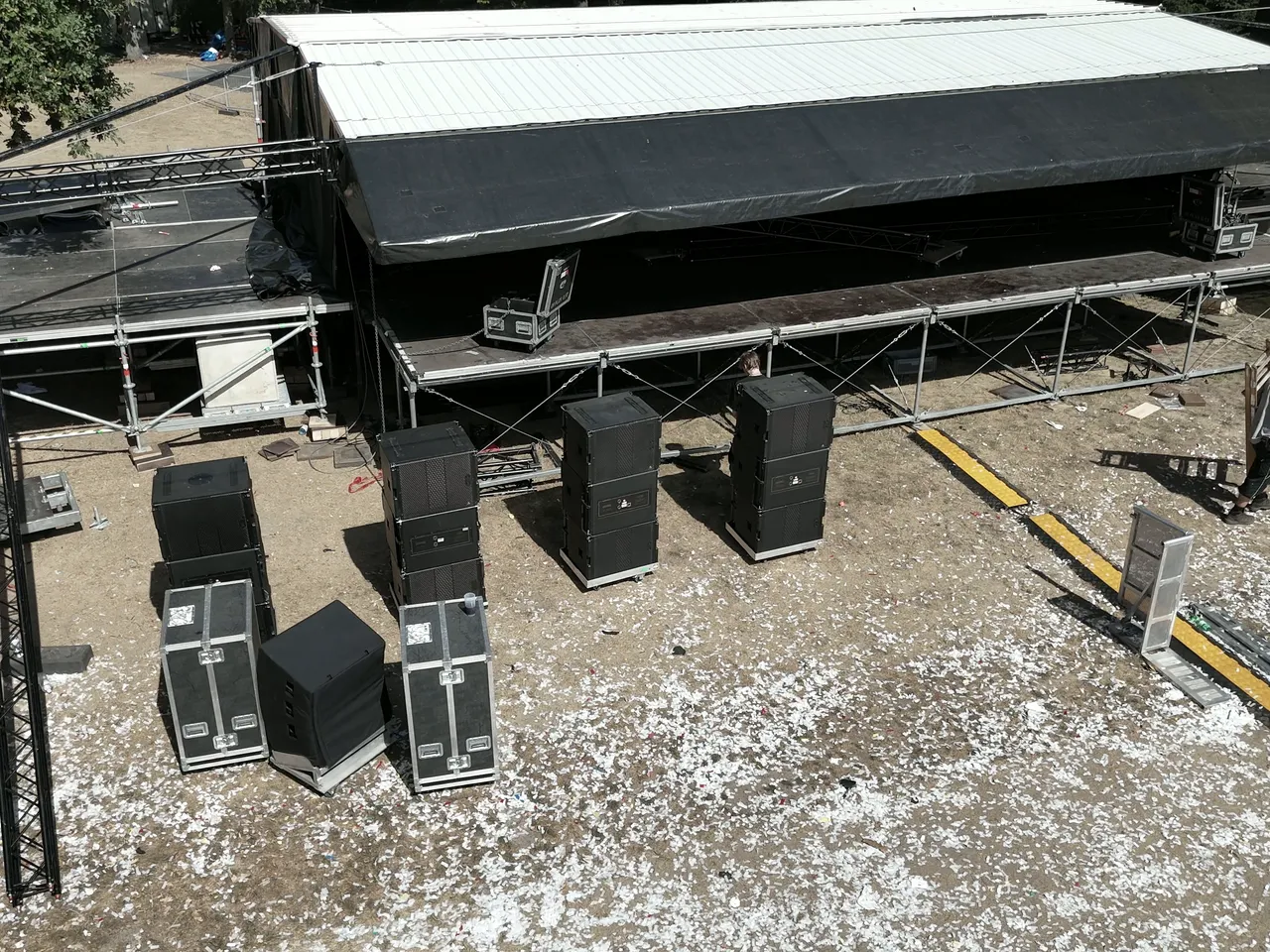 Luftbild einer fertig aufgebauten Bühne mit Dach, davor Subwoofer und Cases