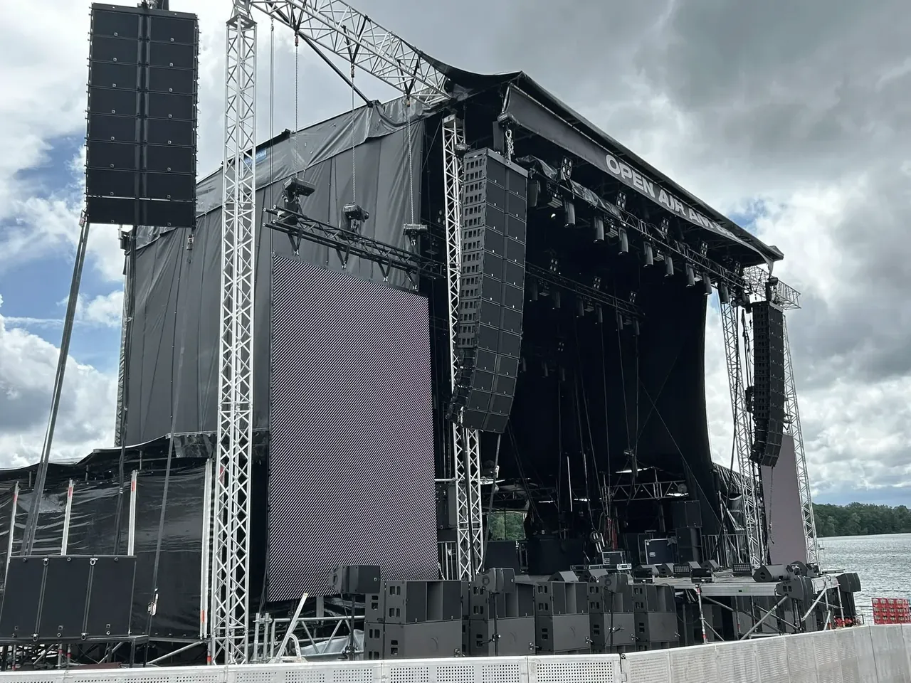 Festivalbühne mit Line-Array und Bühnendach vor bewölktem Himmel