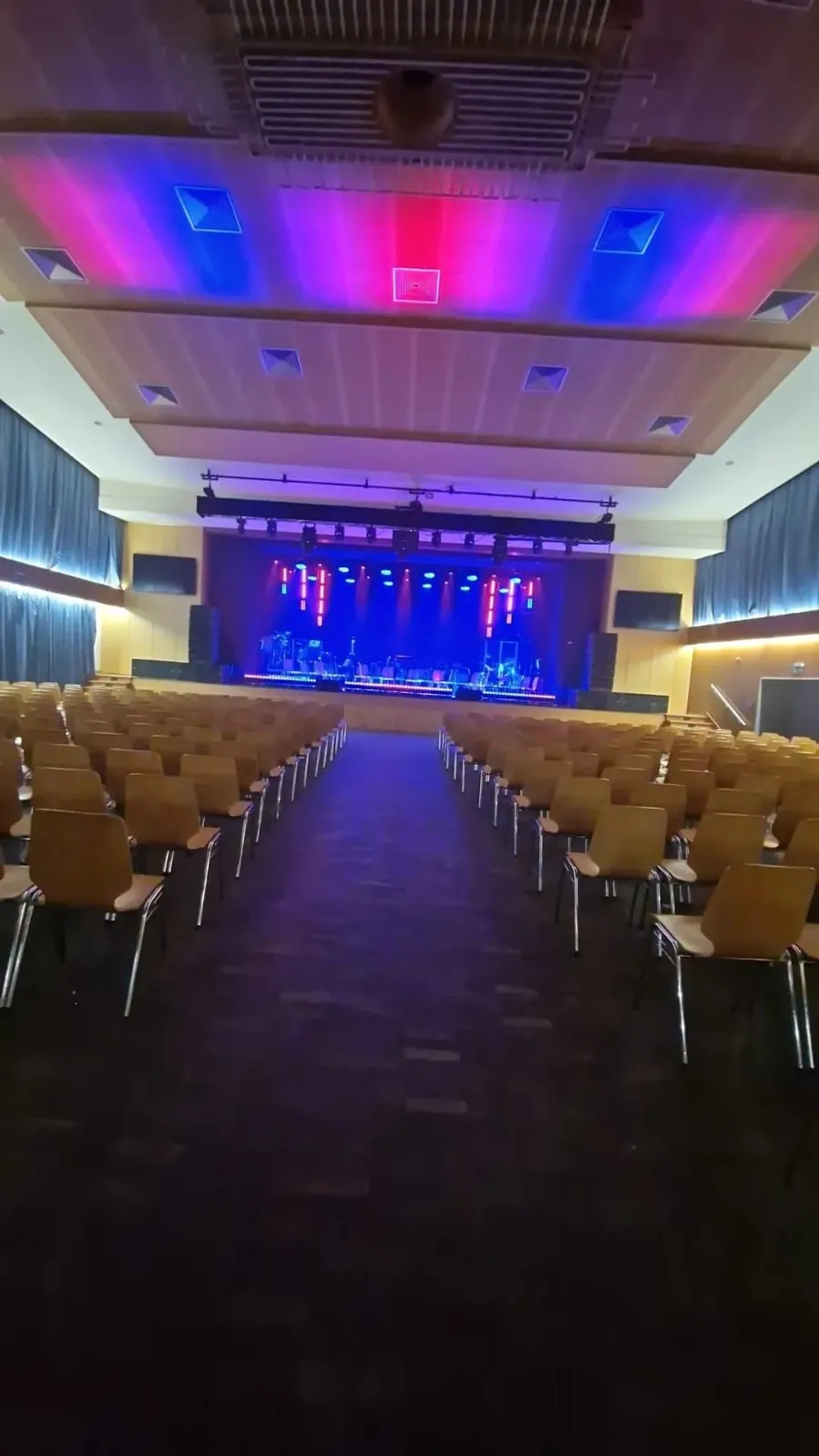 Beleuchtete Bühne mit Traversen und farbigem Licht in einem Saal