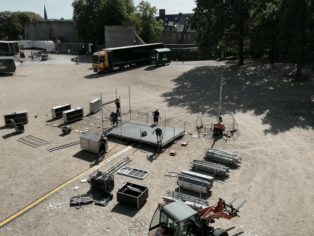 Luftbild eines Veranstaltungsgeländes im Aufbau: Bühne, Lkw und Materialflächen aus der Vogelperspektive